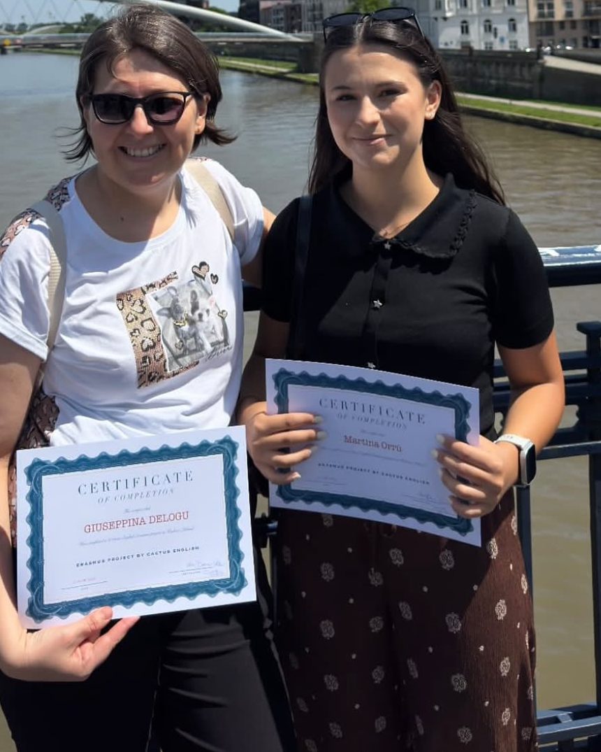 Two participants with their course certificates by the river in Kraków